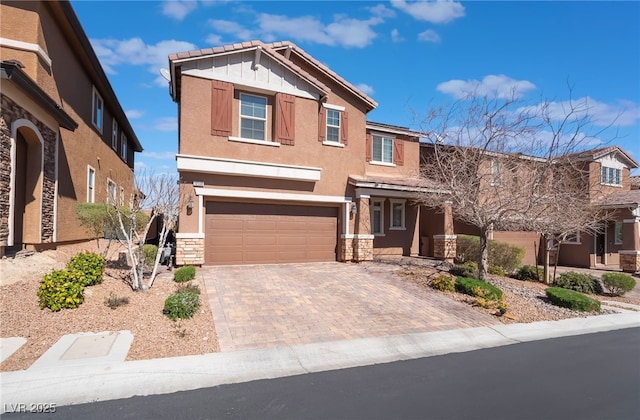 craftsman-style house featuring a garage, stone siding, decorative driveway, and stucco siding