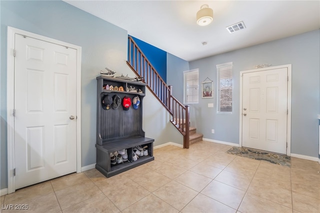 entryway featuring tile patterned flooring, visible vents, baseboards, and stairs