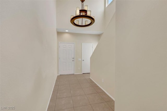 interior space featuring a high ceiling, light tile patterned flooring, and baseboards