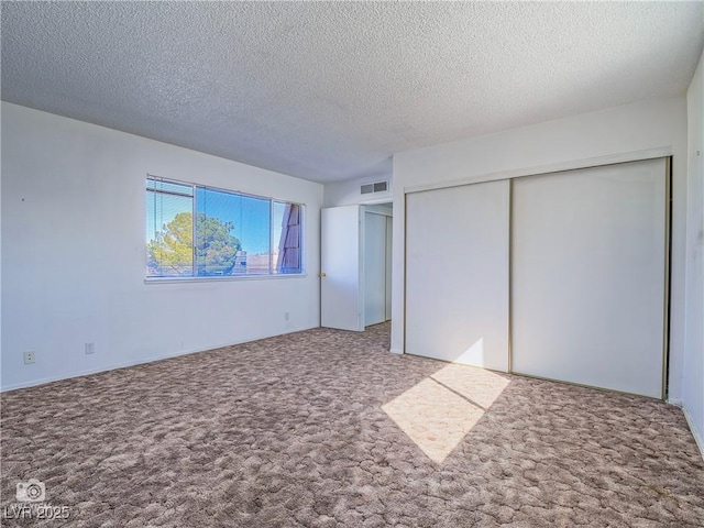 unfurnished bedroom with carpet floors, visible vents, and a textured ceiling