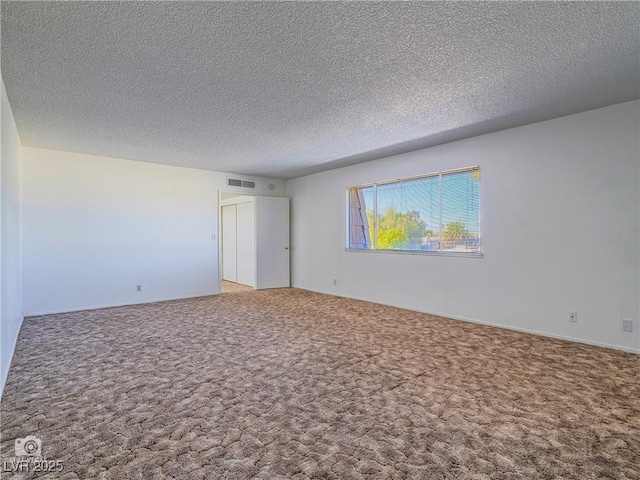 unfurnished room with a textured ceiling, visible vents, and carpet flooring