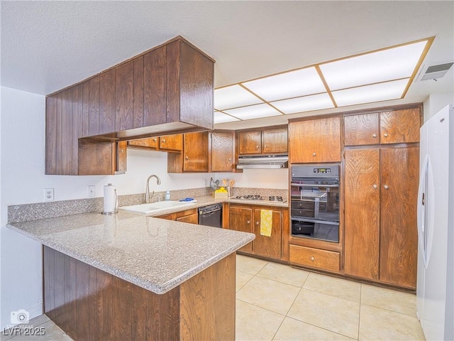 kitchen with a warming drawer, freestanding refrigerator, light tile patterned flooring, a sink, and a peninsula