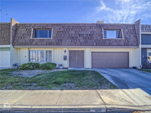 multi unit property featuring board and batten siding, driveway, a garage, and mansard roof