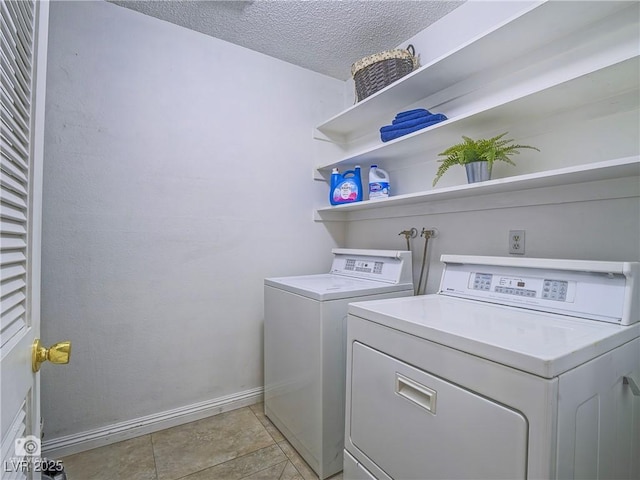 clothes washing area featuring light tile patterned floors, a textured ceiling, laundry area, independent washer and dryer, and baseboards