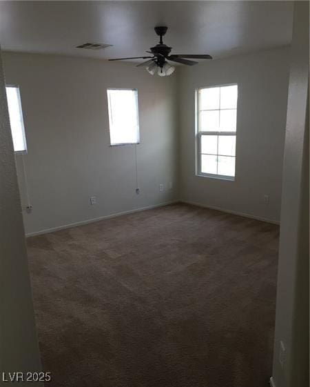 carpeted spare room with baseboards, visible vents, and a ceiling fan