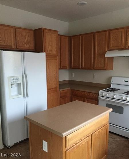 kitchen featuring brown cabinetry, white appliances, a kitchen island, and under cabinet range hood