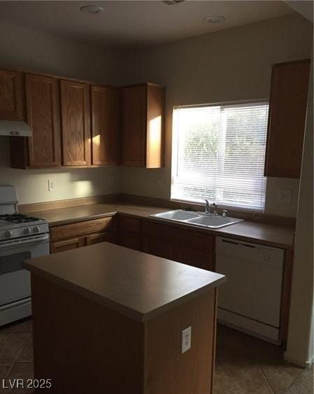 kitchen featuring light tile patterned floors, gas range oven, white dishwasher, under cabinet range hood, and a sink