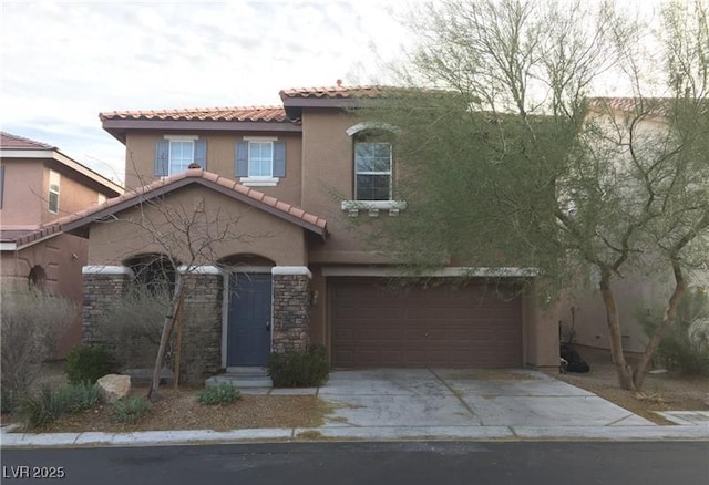 mediterranean / spanish home featuring an attached garage, a tiled roof, stone siding, concrete driveway, and stucco siding