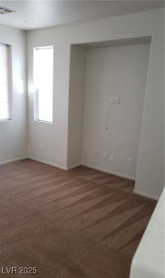 spare room featuring baseboards, plenty of natural light, visible vents, and carpet flooring