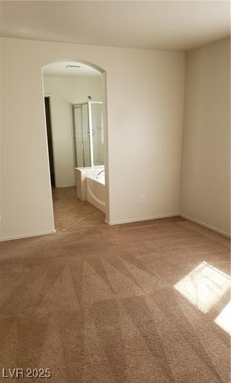 carpeted spare room with arched walkways and baseboards