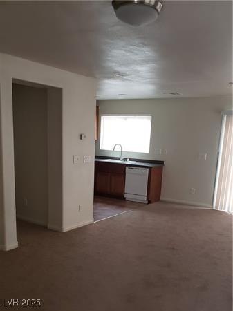 kitchen featuring dishwasher, dark countertops, carpet, and a sink