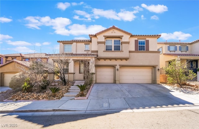 mediterranean / spanish-style home with a garage, concrete driveway, a tiled roof, and stucco siding