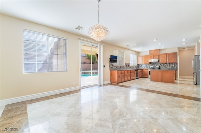 kitchen with stainless steel appliances, backsplash, open floor plan, under cabinet range hood, and baseboards