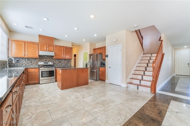 kitchen featuring under cabinet range hood, stainless steel appliances, a sink, visible vents, and a center island