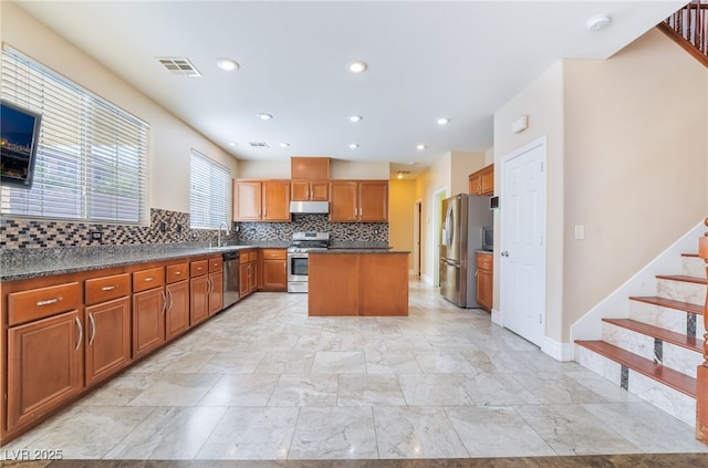 kitchen featuring under cabinet range hood, a kitchen island, visible vents, appliances with stainless steel finishes, and dark countertops