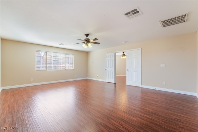 empty room with baseboards, visible vents, and wood finished floors