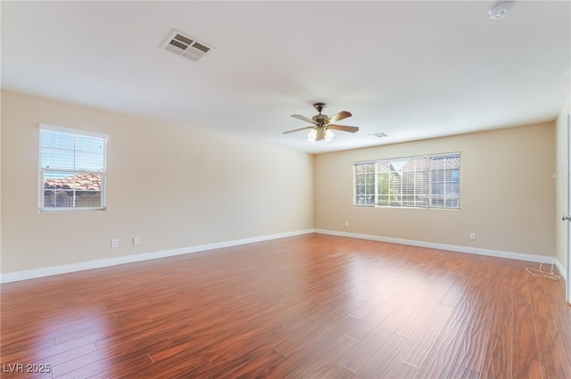 spare room with ceiling fan, light wood finished floors, visible vents, and baseboards