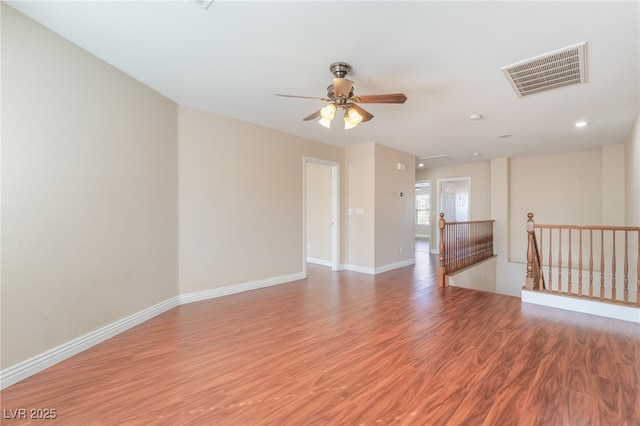 spare room featuring light wood finished floors, a ceiling fan, visible vents, and baseboards