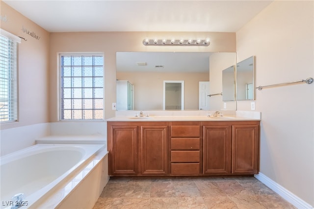 bathroom with a bath, double vanity, and a sink