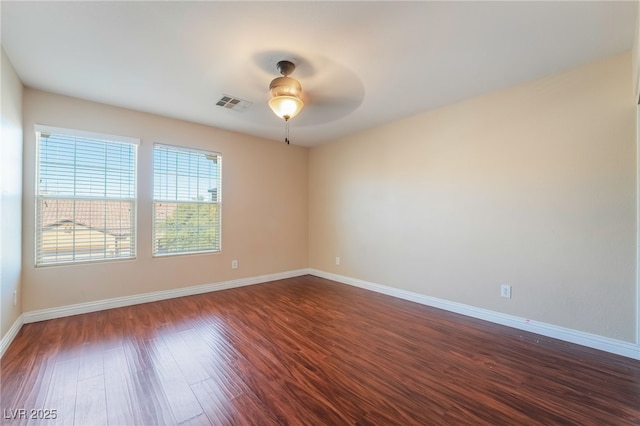 empty room with a ceiling fan, baseboards, visible vents, and dark wood-type flooring