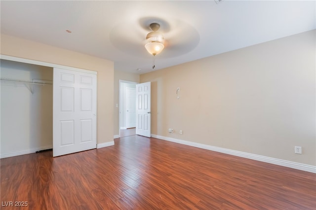 unfurnished bedroom with a closet, wood finished floors, a ceiling fan, and baseboards