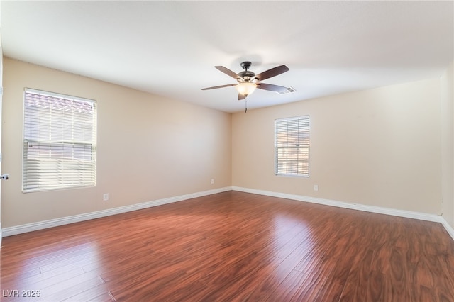 empty room featuring dark wood-style floors, baseboards, and a ceiling fan