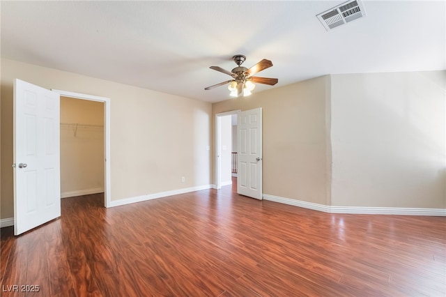 unfurnished room with a ceiling fan, wood finished floors, visible vents, and baseboards