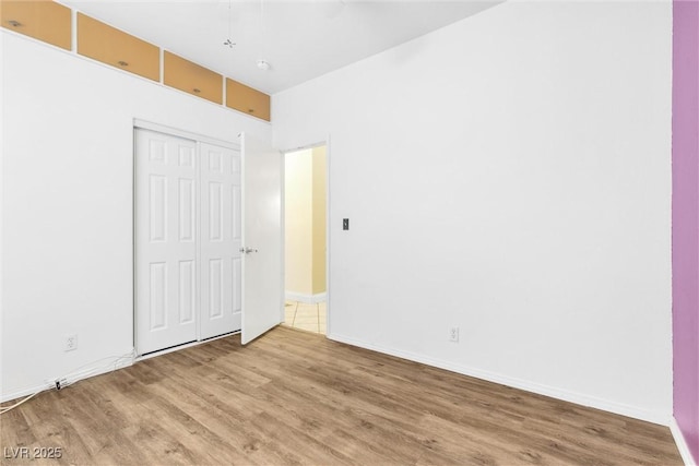 unfurnished bedroom with a closet, baseboards, and wood finished floors