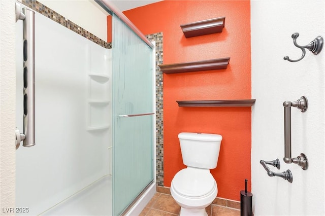 full bath featuring a stall shower, tile patterned flooring, baseboards, and toilet