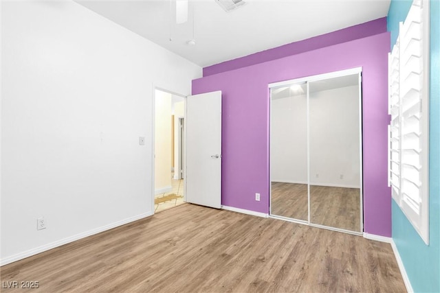 unfurnished bedroom featuring ceiling fan, a closet, baseboards, and wood finished floors