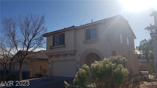 view of front of property featuring a garage, a tile roof, driveway, and stucco siding