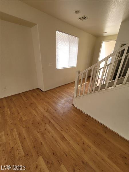 unfurnished living room with stairs, wood finished floors, and visible vents