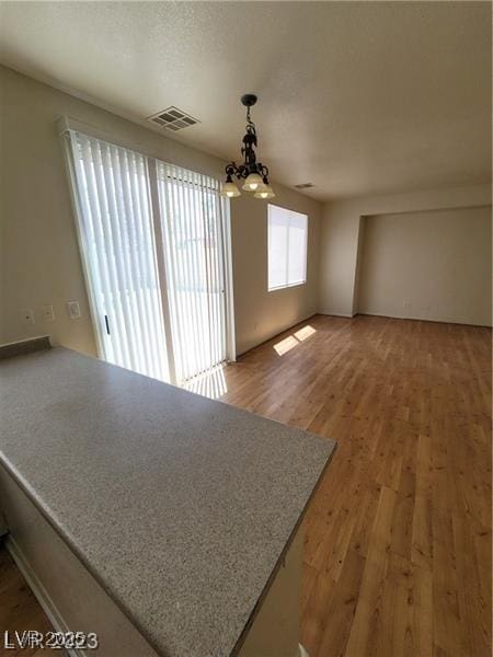 unfurnished room featuring a chandelier, visible vents, and light wood-style floors