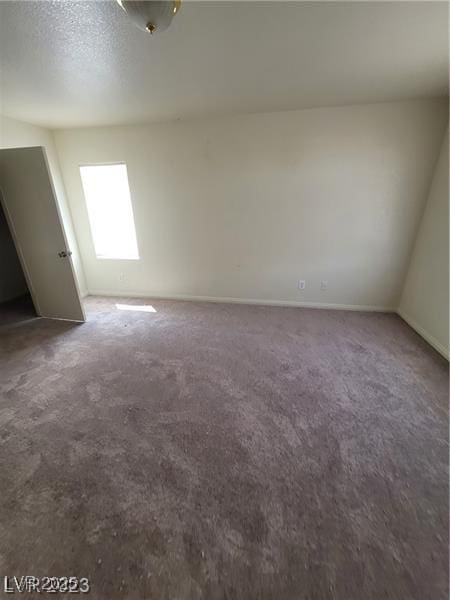 empty room with carpet floors, a textured ceiling, and baseboards