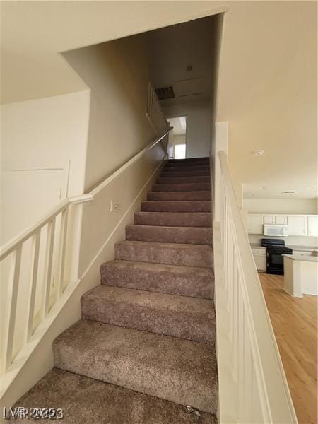 staircase featuring wood finished floors and visible vents