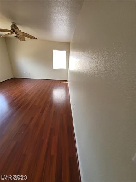 empty room featuring ceiling fan, a textured ceiling, and wood finished floors