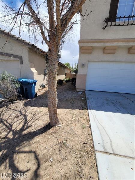 view of side of home with concrete driveway and stucco siding