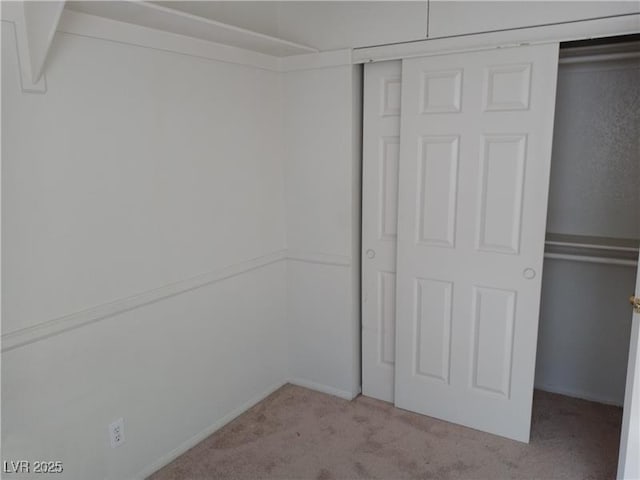 unfurnished bedroom with a closet and light colored carpet