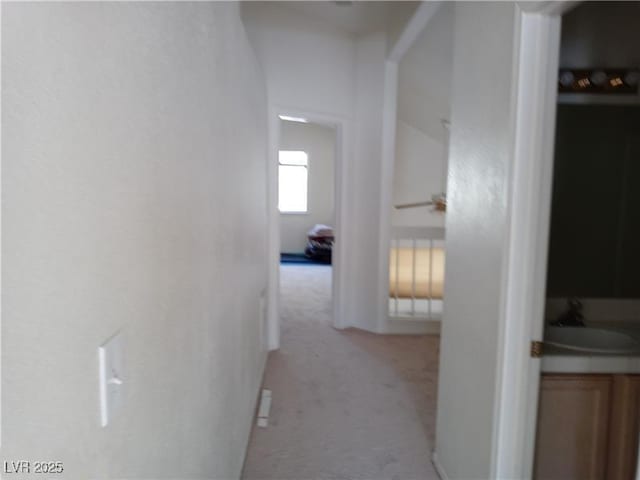 hall with light colored carpet and a sink