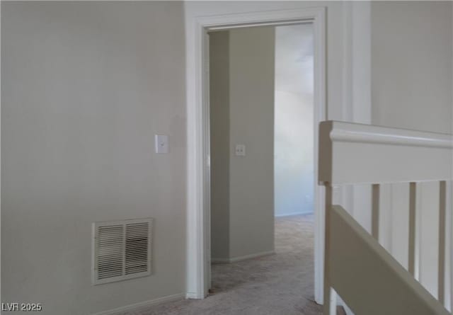 hallway with carpet, visible vents, and baseboards