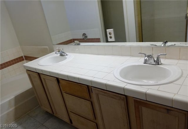 full bath featuring tile patterned flooring, a sink, a bathing tub, and double vanity