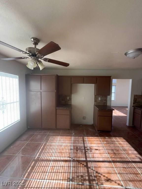 kitchen featuring dark countertops, a ceiling fan, and tile patterned floors