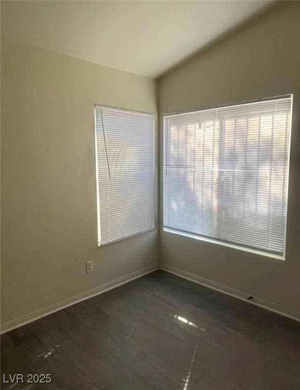 spare room with vaulted ceiling, wood finished floors, a wealth of natural light, and baseboards