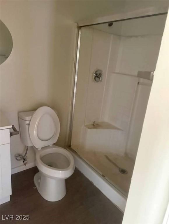 full bath featuring toilet, a shower stall, baseboards, and vanity