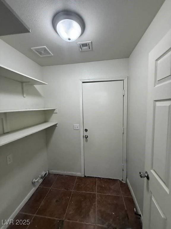 laundry room with laundry area, baseboards, visible vents, and dark tile patterned flooring