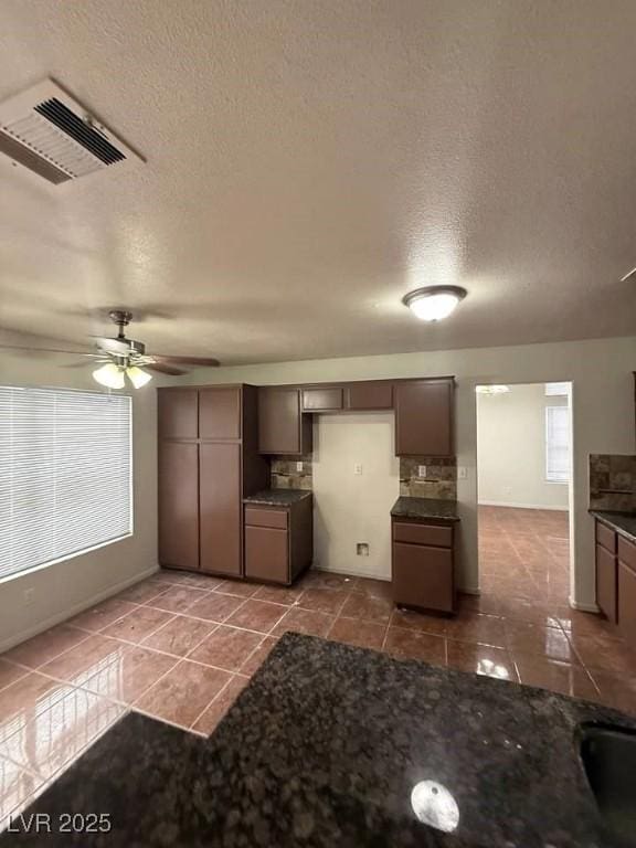 kitchen with dark countertops, visible vents, ceiling fan, a textured ceiling, and dark tile patterned flooring