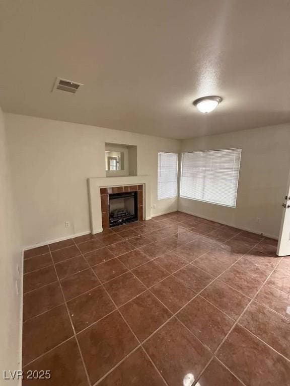 unfurnished living room with dark tile patterned floors, a tile fireplace, and visible vents