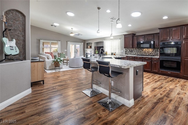 kitchen with dark wood-type flooring, a breakfast bar, visible vents, open floor plan, and black appliances