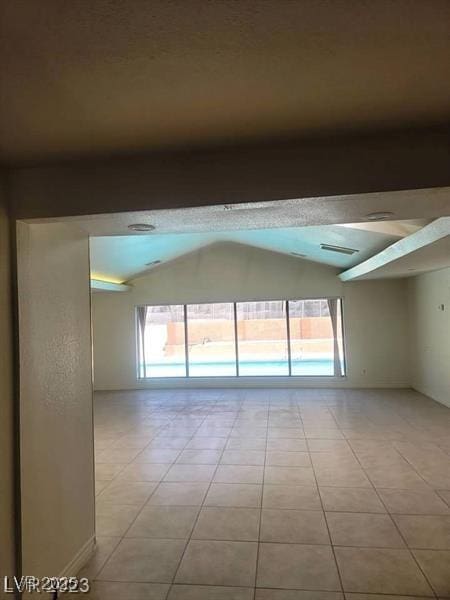 spare room featuring light tile patterned floors, visible vents, and vaulted ceiling