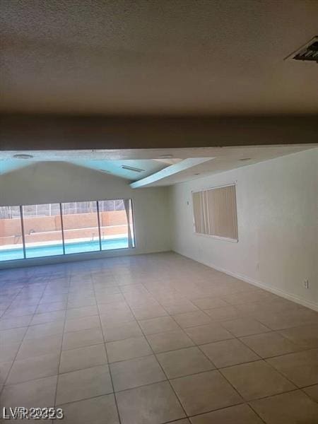 spare room with visible vents, a textured ceiling, beam ceiling, and baseboards